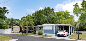 street view of home with grassy lawn and trees